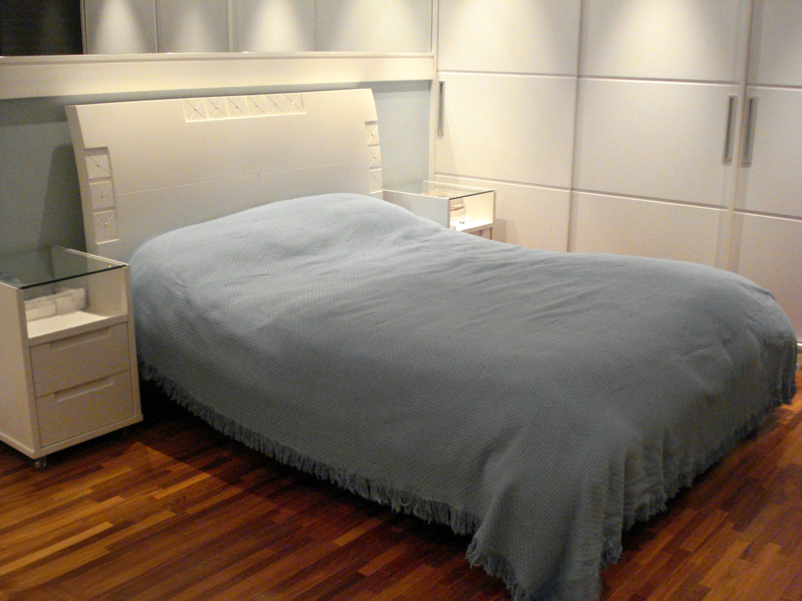 Suíte layout 1: Cama ao lado do armário com destaque para o piso de madeira maciça de cumarú que cobre todo o apartamento, exceto áreas molhadas